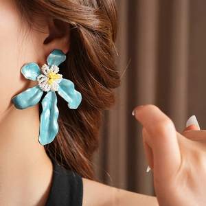 Gros plan de la boucle d'oreille fleur en émail bleu avec centre perlé sur le mannequin
