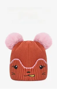 Détail du bonnet en maille orange avec pompons roses et broderie visage d'animal mignon