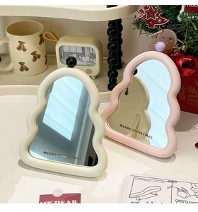 Close-up of pink and cream wavy desktop mirrors with gold Merry Christmas lettering