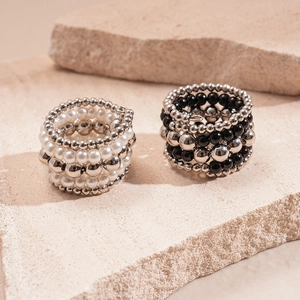 Detail of layered beaded rings with white pearls and silver beads on a stone base