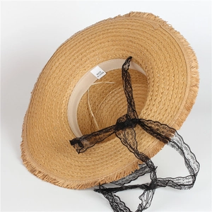 Detailed macro view of woven straw hat texture with black lace strap and frayed brim