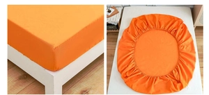 Detail view of bright orange fitted sheet with elastic band and smooth fabric finish