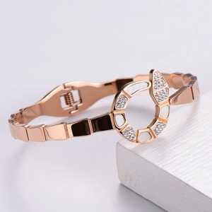 Detail of rose gold snake bracelet featuring white shell inlay and sparkling crystals