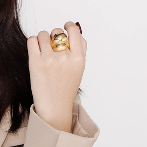 Detail of a gold double-layer teardrop stainless steel ring worn on a model's hand