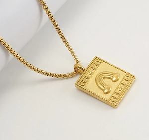 Vue détaillée du pendentif carré en or avec gravures de nuages et arc-en-ciel