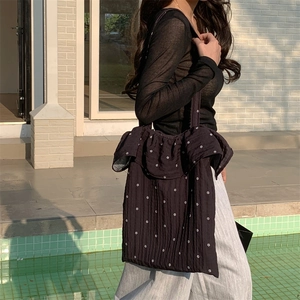 Detail of floral tote bag with ruffle trim shown on model by a sunny outdoor pool