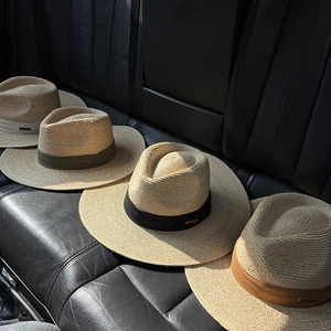 Detail of four natural raffia fedora hats with colorful bands on a leather car seat