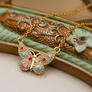 Macro shot of gold butterfly pendant with colorful enamel and zircon stones