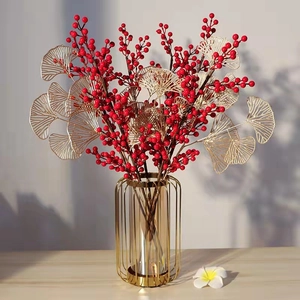 Detail view of red berry branches and golden leaves in a glass vase for home decor
