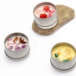 Detailed macro view of scented soy candles with dried flowers and healing crystals in tin cans