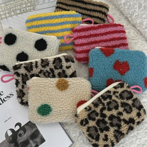 Flat lay of small plush heart pouches with leopard and dot patterns on a soft background