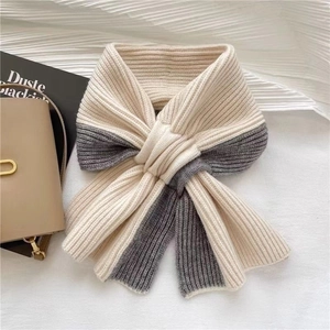 Detail of beige and grey knitted scarf with cross knot styling on textured background
