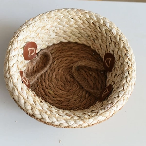 Handwoven round seagrass flower basket with dual handles and leather buckles on white background