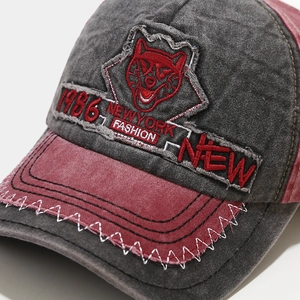 Close-up of vintage washed denim baseball cap with wolf head embroidery and contrast stitching