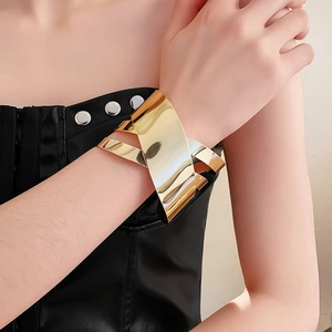 Detailed view of wide gold irregular metal cuff bracelet with crisscross geometric design