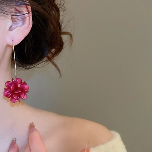 Dettaglio degli orecchini a forma di fiore 3D rosa acceso indossati da una modella