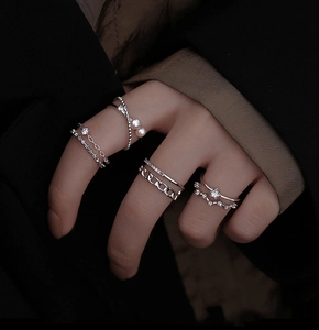 Detail of silver rings set with pearls and zircon star accents on model's hand