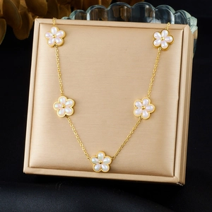 Gold-plated stainless steel necklace featuring five white flower motifs on a jewelry display box