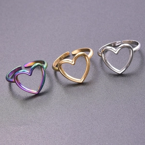 Three open heart rings in iridescent, gold, and silver finishes on a textured dark base