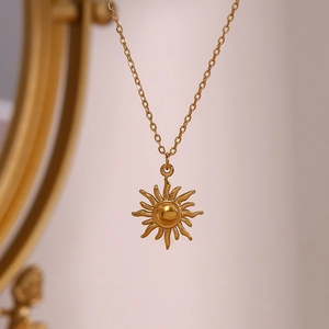 Macro detail of golden sun pendant on a minimalist stainless steel O-chain necklace