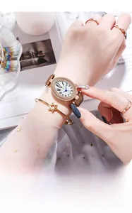 Close-up of elegant oval rhinestone watch with brown leather strap and gold star bracelet