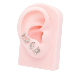Silver heart and butterfly zircon stud earrings set on a silicone ear model display