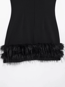 Détail de l'ourlet de robe noire avec bordure en plumes luxueuses et tissu lisse