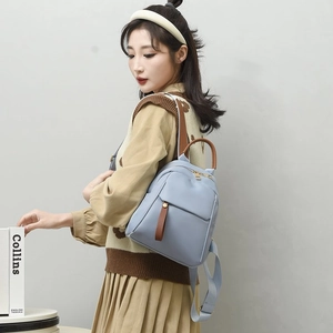 Dettaglio zaino in nylon azzurro con cinghie marroni e componenti in metallo dorato