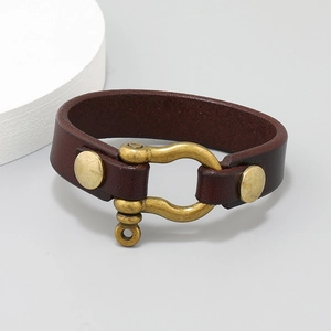 Close-up of brown leather bracelet featuring a vintage brass horseshoe U-shackle clasp