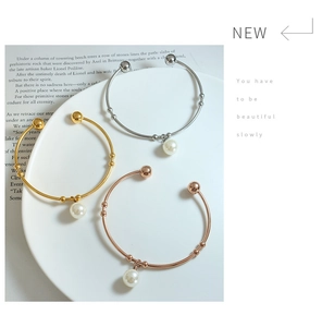 Detailed view of three-color minimalist bracelets with pearls on a white ceramic tray