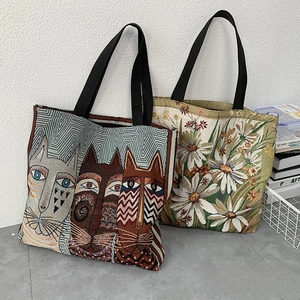 Detailed view of canvas tote bags with artistic cat print and daisy floral embroidery