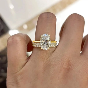 Nahaufnahme eines großen ovalen Diamantrings und zwei schimmernden Pavé-Hochzeitsbändern