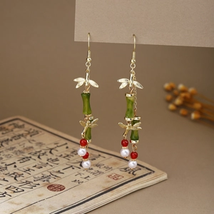 Close-up of Oriental style earrings with green bamboo beads and vintage gold dragonfly