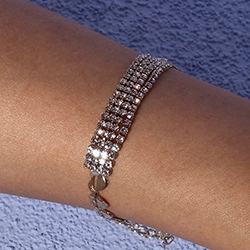 Close-up of a silver four-row rhinestone bracelet with an adjustable chain on a wrist