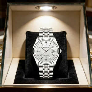 Close-up of a silver steel watch with white dial and calendar display on a black pillow