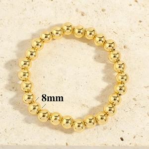 Detailed macro view of 8mm polished gold bead stretch bracelet on stone surface