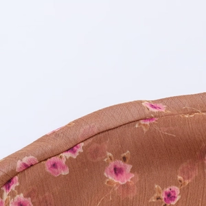Close-up of brown chiffon fabric featuring detailed pink floral pattern and soft texture