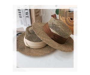 Detail of natural straw sun hats featuring elegant brown and beige wide silk ribbons