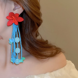 Detail of beaded tassel earrings with red fabric flower and blue beaded strands