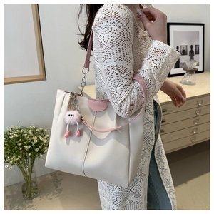 Dettaglio della borsa tote bianco crema con inserti rosa e ciondolo di peluche per donna