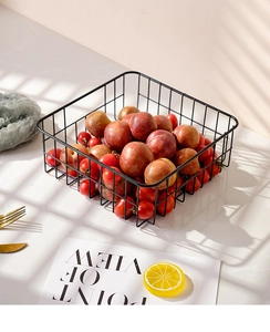 Close-up of black metal grid fruit basket on marble surface with grid shadows