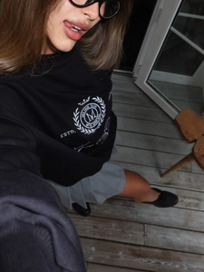 Détail d'un sweat-shirt noir à col rond avec broderie blanche MIA MUR sur la poitrine