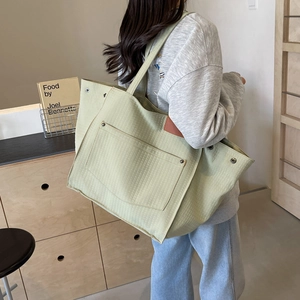 Quilted sage green canvas tote bag with outer pocket and leather label shown on shoulder