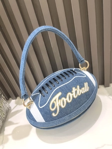Detail of blue denim football-shaped handbag with embroidery and gold hardware