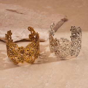 Close-up of intricate hollow flower patterns on gold and silver metal cuff bracelets