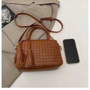 Detail view of brown woven handbag with side tassels and textured leather finish