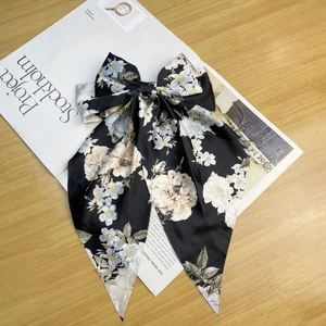 Detail of vintage black satin ribbon bow hair clip with camellia floral patterns