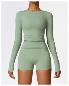Detail view of sage green long-sleeve yoga top with ruched waist and high-waisted shorts