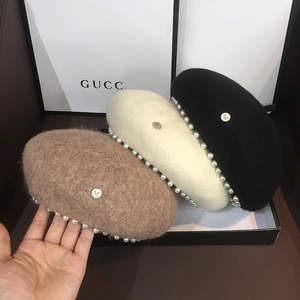 Detail of wool beret set with elegant pearl trim and metal M letter hardware