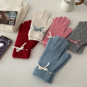 Flat lay of colorful knit gloves with bow details and matching winter accessories